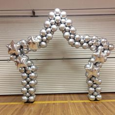 an arch made out of silver balls and stars on a wooden floor in front of a garage door