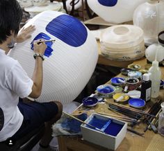 a man sitting in front of a large blue ball on top of a wooden table