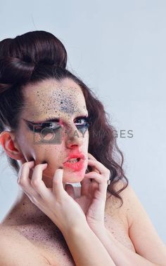 a woman with black makeup and glitter on her face posing for the camera in front of a white background