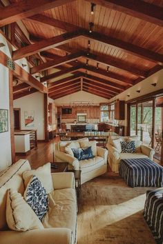 a living room filled with lots of furniture and wooden ceiling beams on top of a hard wood floor