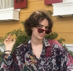 a person with sunglasses on standing in front of a house