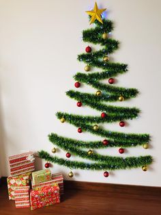 a christmas tree with presents under it in front of a wall mounted ornament