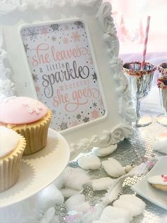 cupcakes are sitting on plates in front of a framed sign that says she leaves a little sparkle wherever she goes