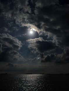 the moon is shining brightly in the dark sky above the ocean and clouds are reflected on the water