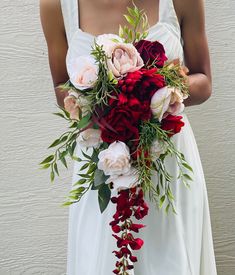 a bride holding a bouquet of red and white flowers