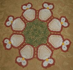 a crocheted doily with white and red birds sitting on top of it