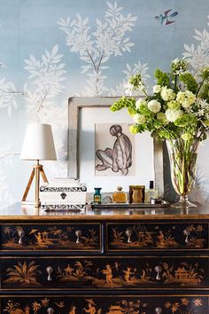 a dresser with flowers and pictures on the wall