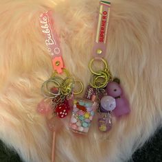 This Keychain One Is Pink And The Other One Is Purple It Glow In The Dark One Of Them Has Cup Ball Inside And Sparkly Glitter With A Lollipop On Air, A Dice Cup, And A Wristband The Purple Has I Wristband The Purple One Goes In The Dark With A Teddy Bear On There And Cup And Wine Glass Pink Harajuku Style Jewelry Gift, Trendy Luminous Jewelry For Gifts, Fun Pink Keychain As Gift, Fun Pink Keychain For Gifts, Novelty Pink Keychain For Gift, Customized Pink Keychains, Trendy Pink Jewelry For Personal Use, Customized Pink Keychains As Gifts, Customized Pink Keychain As Gift