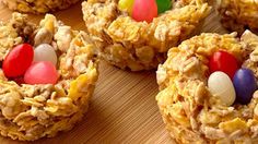 an assortment of candy cornflakes are arranged on a cutting board with eggs and candies