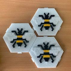 three bees made out of legos sitting on top of a wooden table next to each other