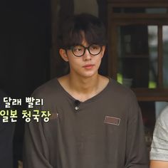 two young men standing next to each other in front of a door with korean characters on it