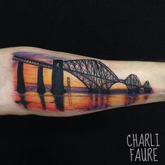 a man's arm with a painting of a bridge on it