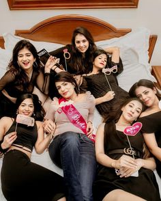 a group of young women laying on top of a bed holding lollipops