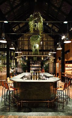 a bar with several stools and lights hanging from it's ceiling in a restaurant