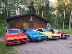 four classic muscle cars parked in front of a building