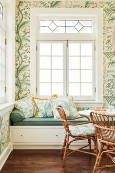 a window seat in the corner of a room with green wallpaper and bamboo chairs