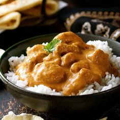 a bowl filled with rice and meat covered in gravy on top of a table