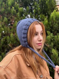 a woman with red hair wearing a blue knitted hat and scarf on her head