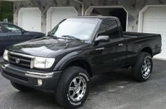 a black pickup truck parked in front of a garage