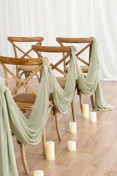 the chairs are covered with draping and lit candles in front of them on the floor