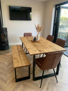 a wooden table with two brown chairs next to it and a wood stove in the background