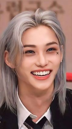 an image of a woman with grey hair and piercings on her forehead smiling at the camera