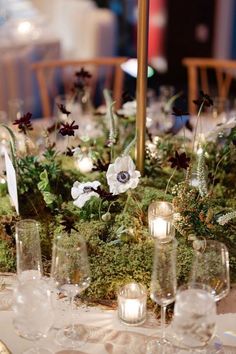 Romantic moss-covered centerpiece with white anemones, dark blooms, and sprigs of greenery, accented by flickering candles. Moss Wedding Centerpiece, Elegant Table Decor, Romantic Centerpieces, White Anemones, Moss Wedding, Moss Decor, White Anemone