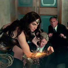 the wonder woman is working on her costume in front of other men and one man