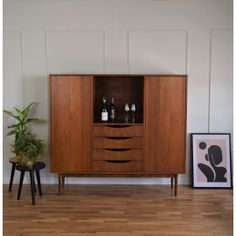 a wooden cabinet sitting on top of a hard wood floor next to a potted plant