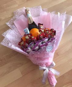 a bouquet of chocolates, an orange and a bottle of champagne on a wooden floor