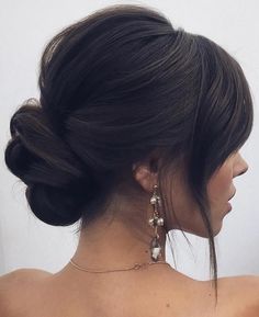 a woman with her hair in a low bun and earrings on top of her head