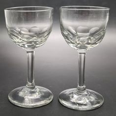 two wine glasses sitting next to each other on a black surface with rocks in them