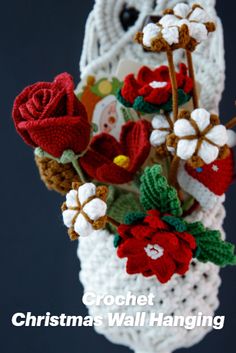 crochet christmas wall hanging with red and white flowers on it's side