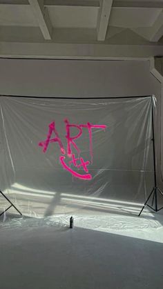 an empty photo studio with pink spray paint on the wall and white backdrop behind it