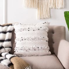 a couch with some pillows on top of it next to a wall hanging from the ceiling