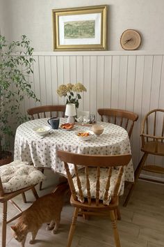 a dining room table with two chairs and a cat on the floor next to it