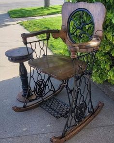 an old fashioned sewing machine sitting on top of a wooden chair next to a bush