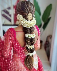 a woman with long hair and flowers in her hair is wearing a red sari