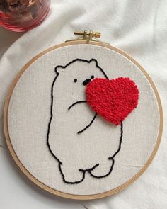 a white bear with a red heart in it's mouth