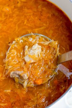 a ladle full of soup being stirred with a wooden spoon