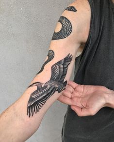 a man holding his arm with an eagle tattoo on it