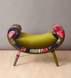 a blue chair with colorful designs on it's back and legs, sitting in front of a white wall