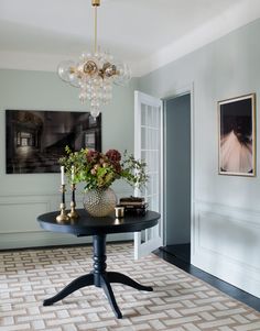 a dining room table with vases and flowers on it in front of a doorway