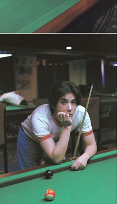 a man leaning over a pool table with his hand on the cues and looking up