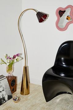 a black and gold lamp sitting on top of a table next to a vase with flowers