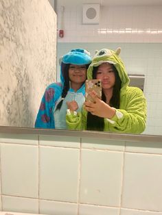 two women taking a selfie in the bathroom mirror with their cell phone and towel on