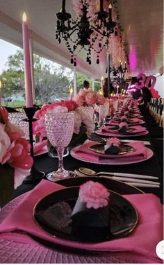 the table is set with pink and black plates, silverware, and napkins