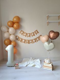 a birthday party with balloons, cake and other items on the floor in front of a wall