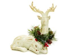 a white deer statue sitting on top of a table next to a pine cone wreath