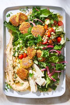 a white plate topped with salad and meat patties